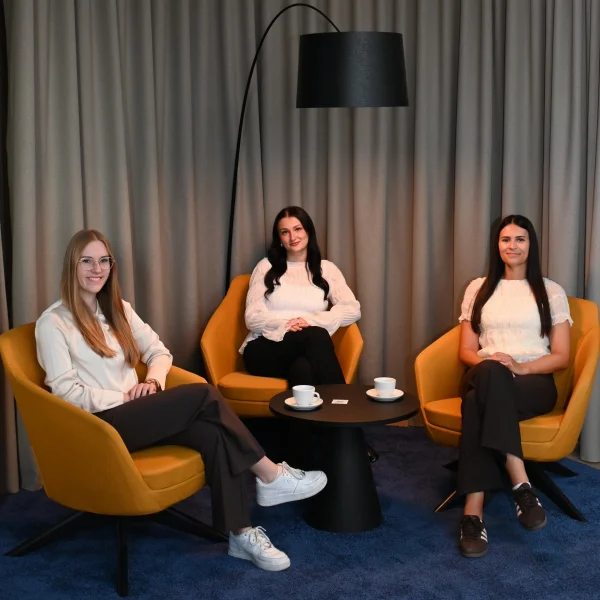3 Frauen sitzen auf Stühlen und schauen in die Kamera