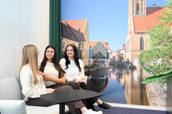 Drei Kolleginnen sitzen auf einer Couch und lachen 